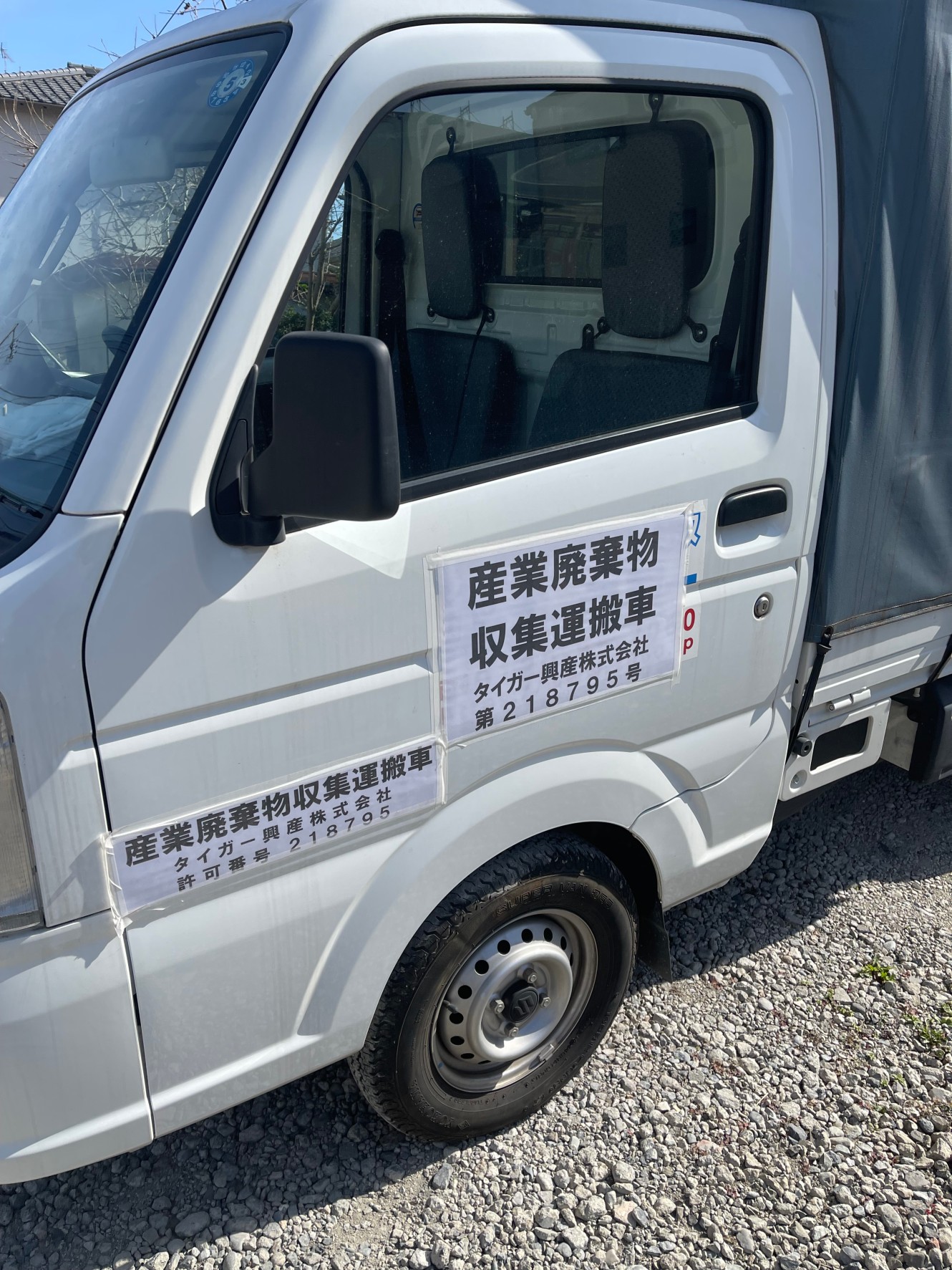 産業廃棄物収集運搬車の側面表示。「産業廃棄物収集運搬車」の文字と会社名が入っている