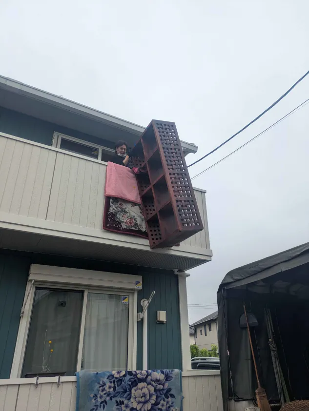 2階ベランダから家具を吊り下げている様子