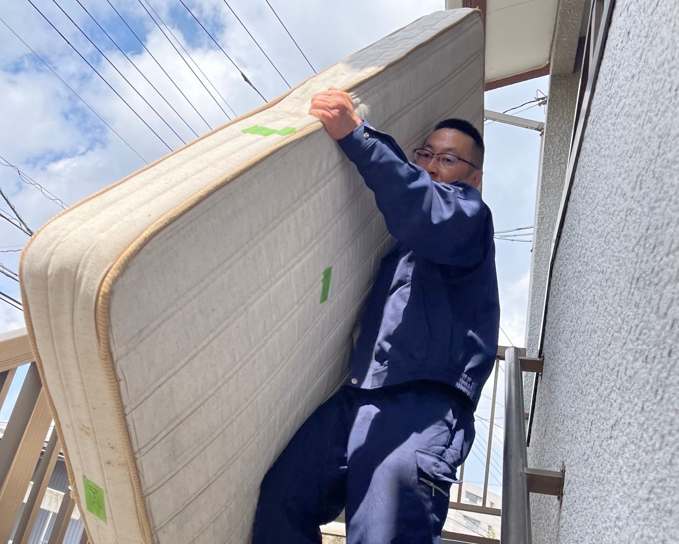 階段からマットレスを運び出している作業員