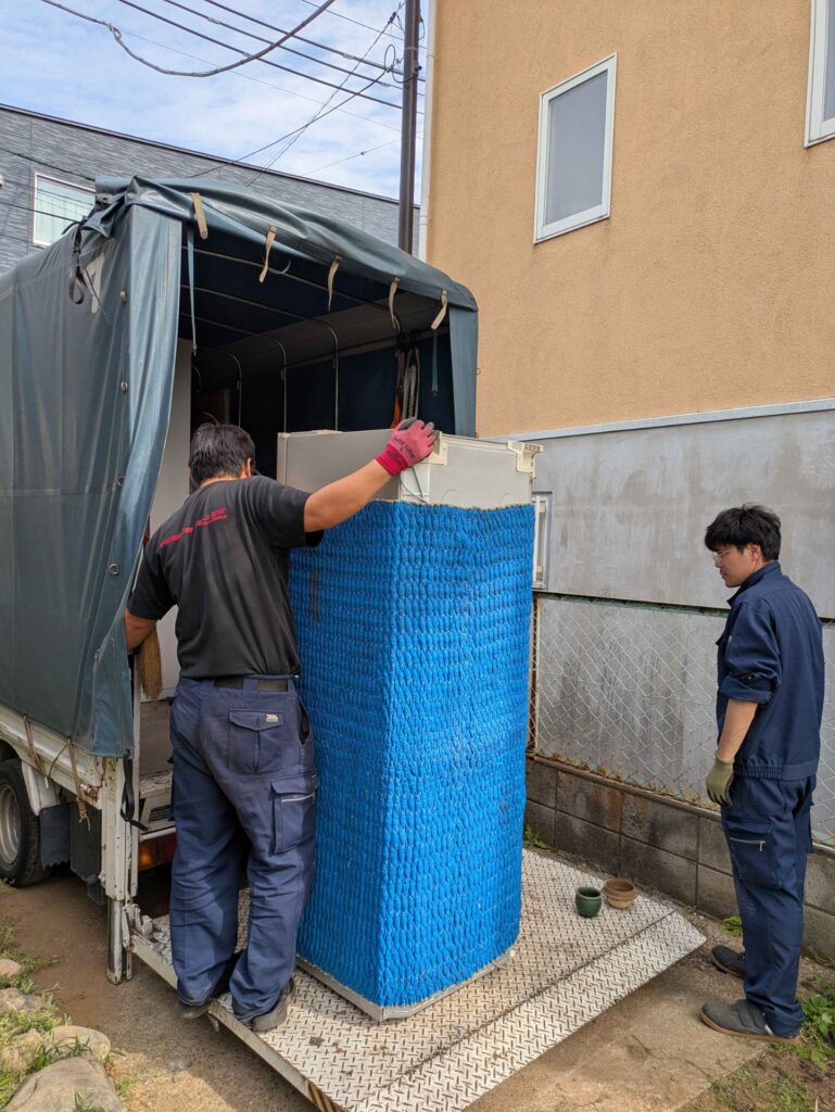 養生した冷蔵庫をトラックの荷台へ積み込む様子