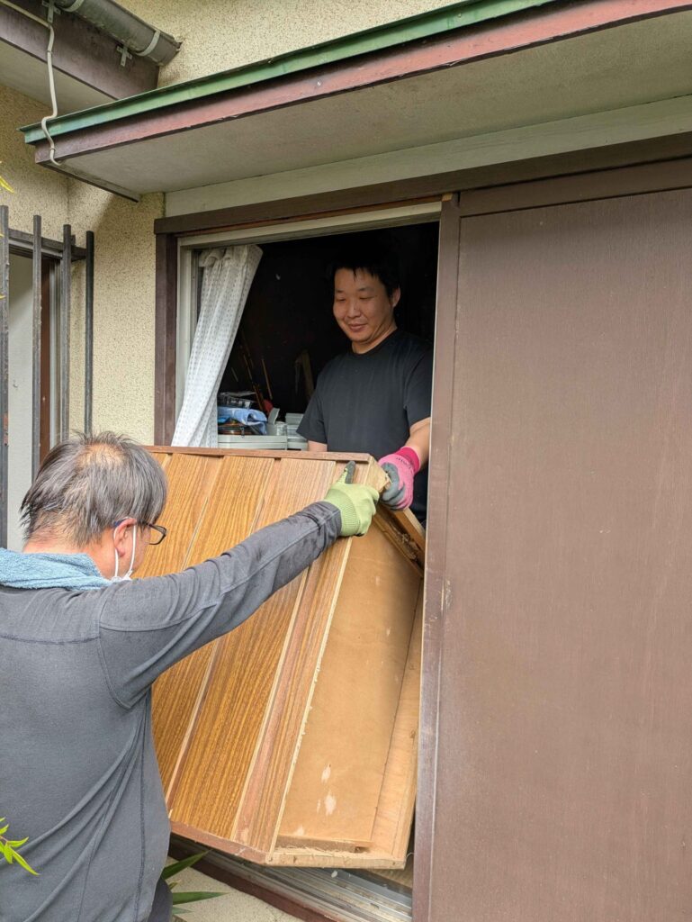 和室の窓から屋外へ家具を受け渡している様子
