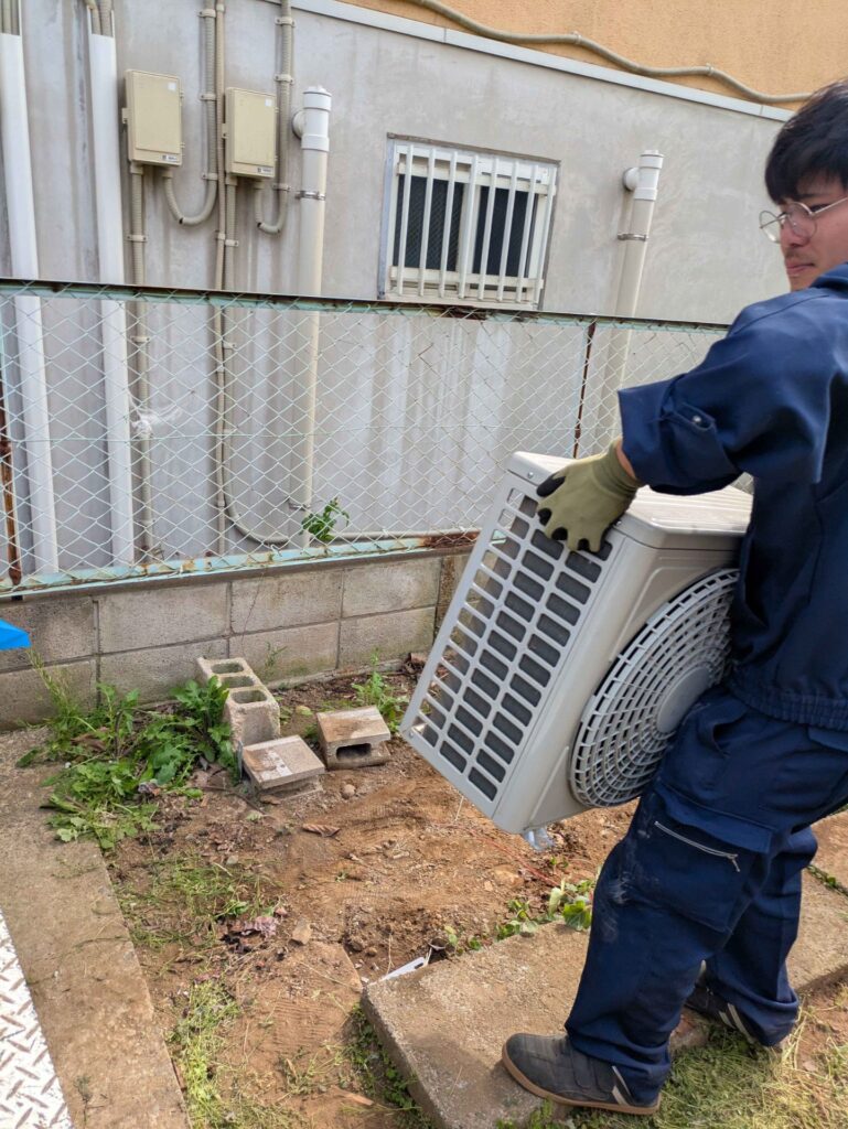 取り外した室外機を運ぶスタッフ