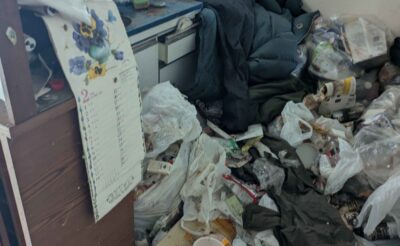 作業前の台所。床一面に生活ごみと衣類が積み重なった状態