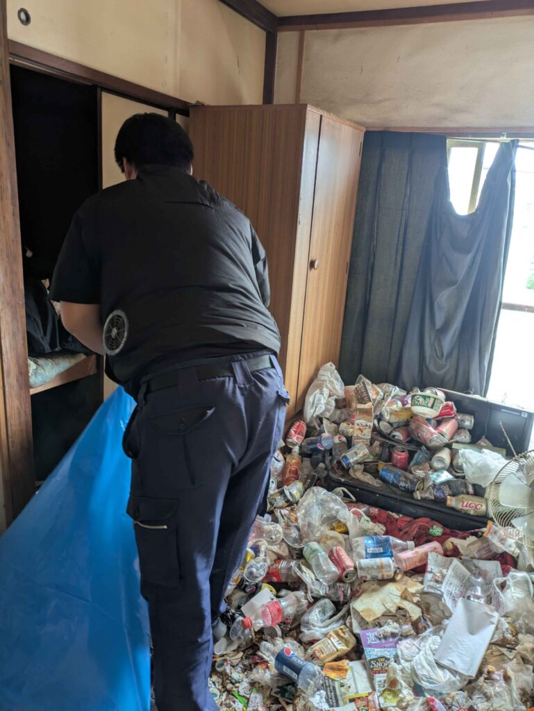 和室で生活ごみを大型の袋に詰めるスタッフ