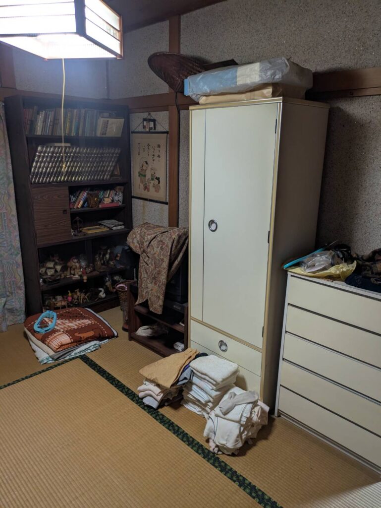 作業前の2階の和室。洋服ダンス・整理ダンス・本棚と衣類が残っている