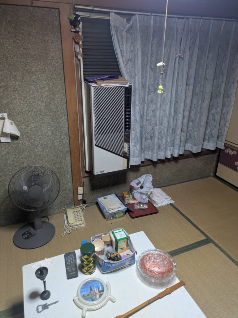 作業前の和室。窓にウインドエアコンが取り付けられ、扇風機や電話台が残っている