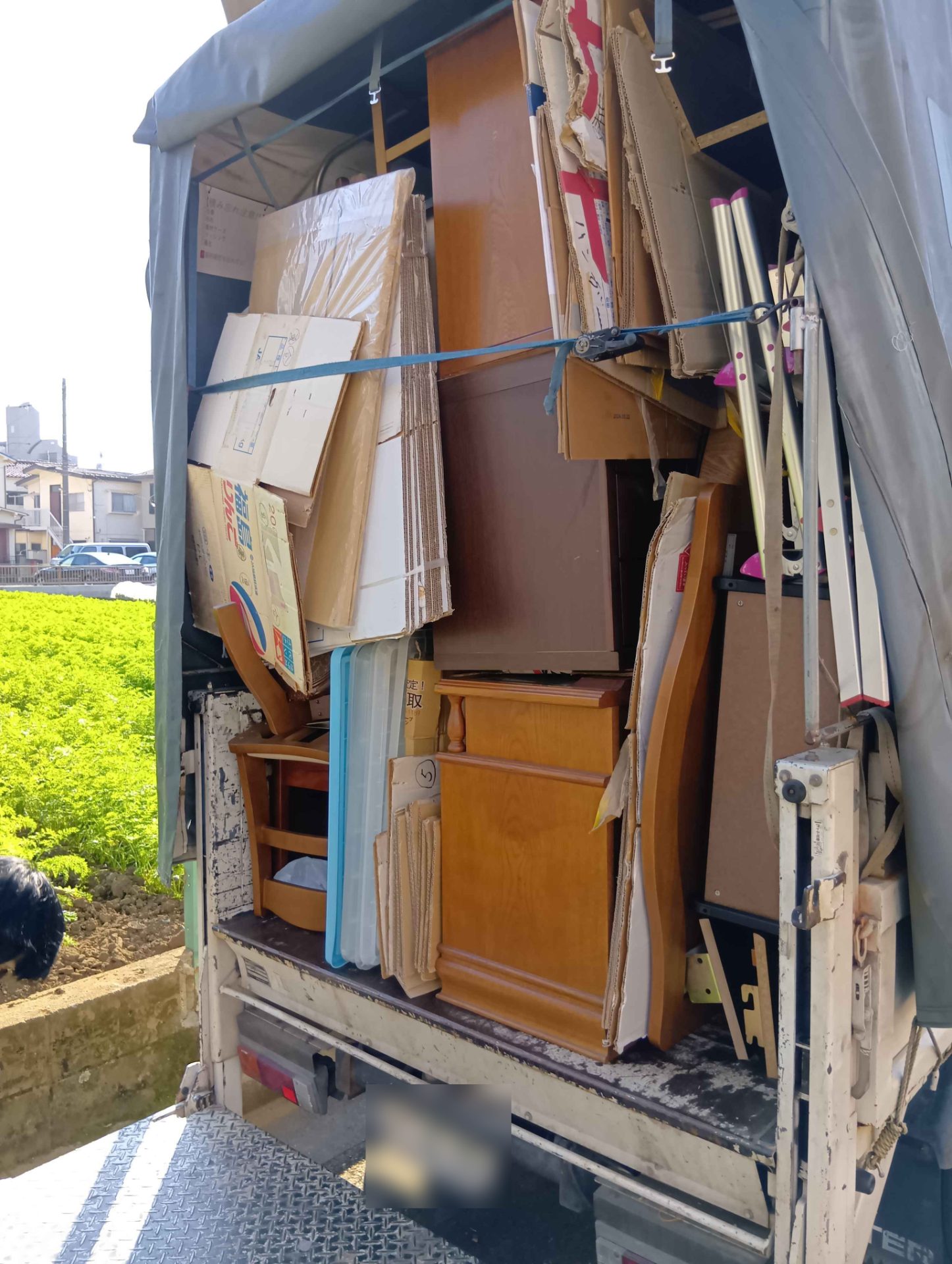 木製の家具と段ボールをベルトで固定したトラックの荷台