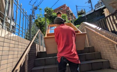 食器棚を担いで外階段を下りる当社スタッフ