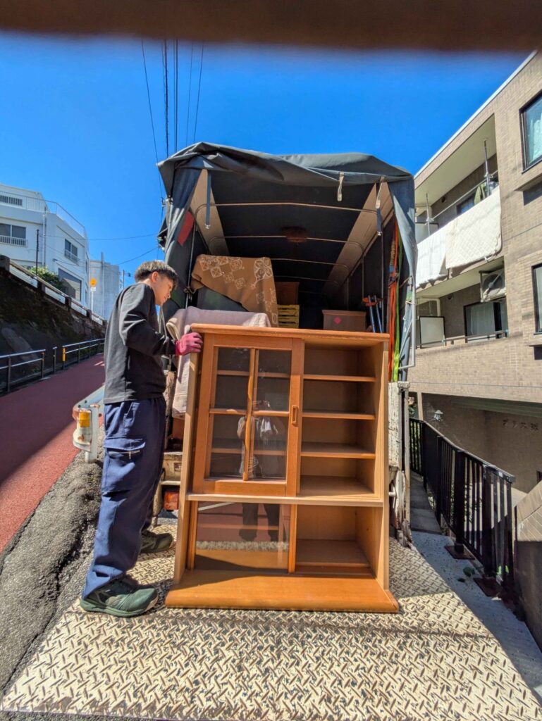 ガラス扉の食器棚をトラックの荷台へ積み込む当社スタッフ