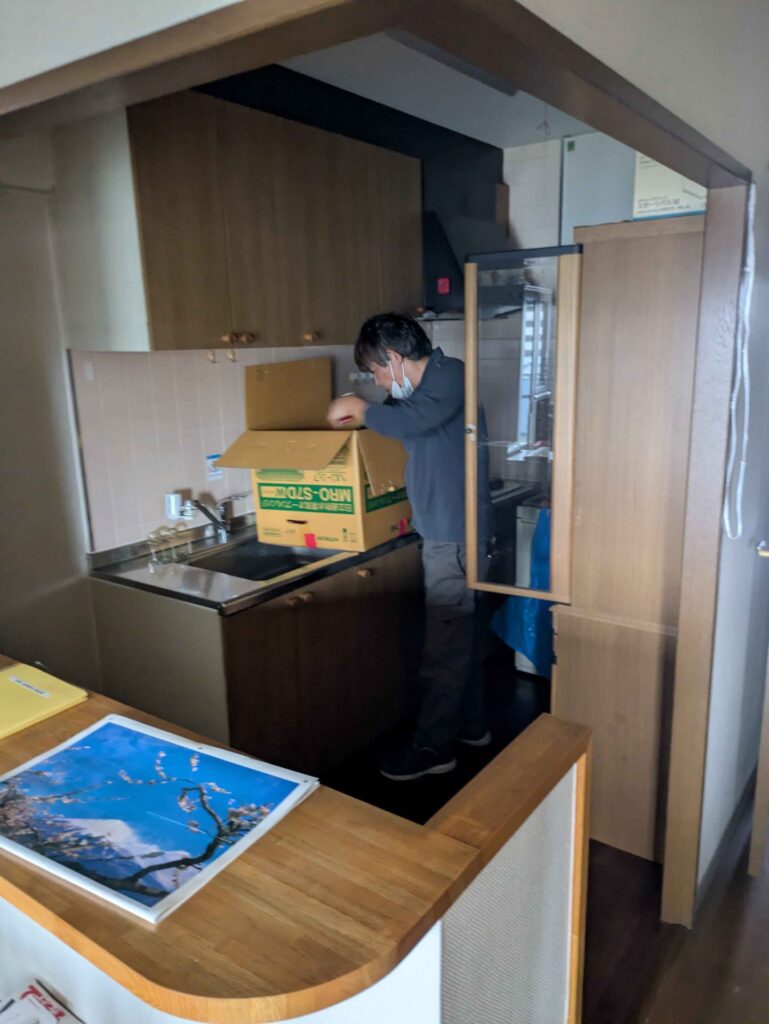 キッチンで食器や小物を段ボールに詰めて分ける当社スタッフ