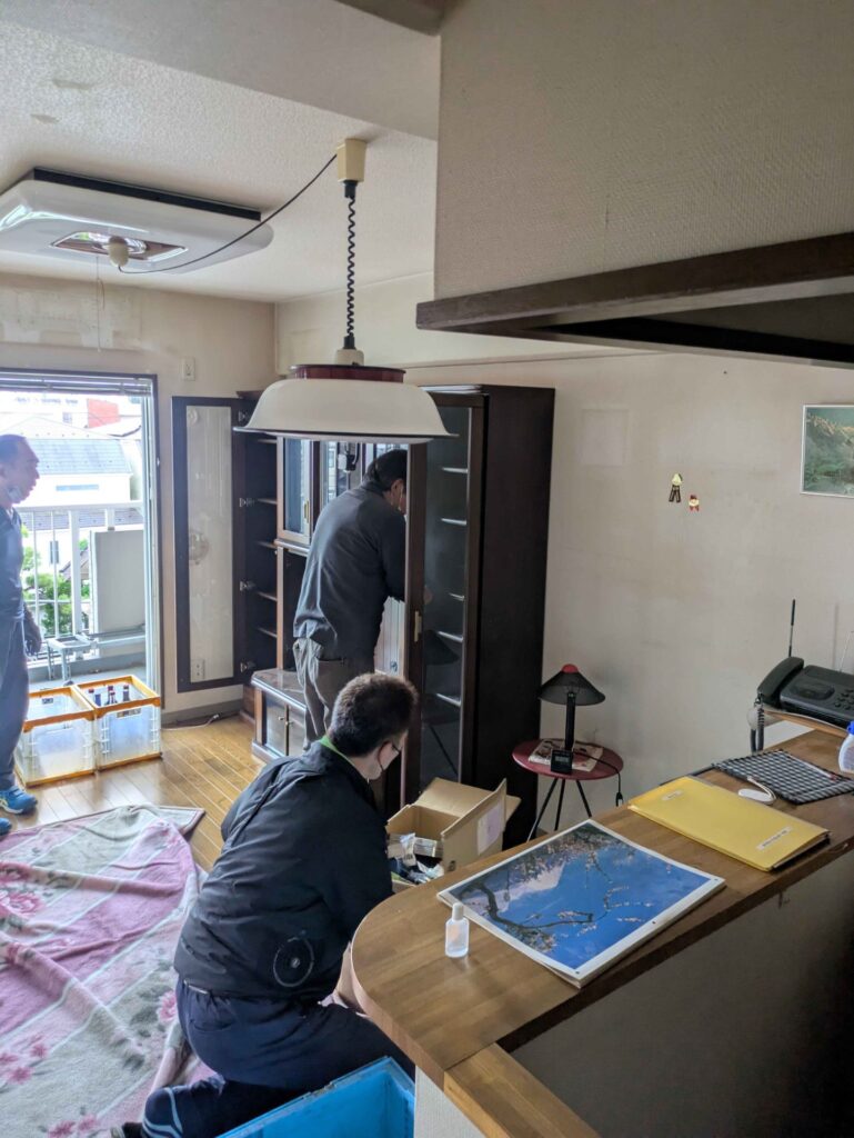 リビングで残された家具や小物を仕分けする当社スタッフ