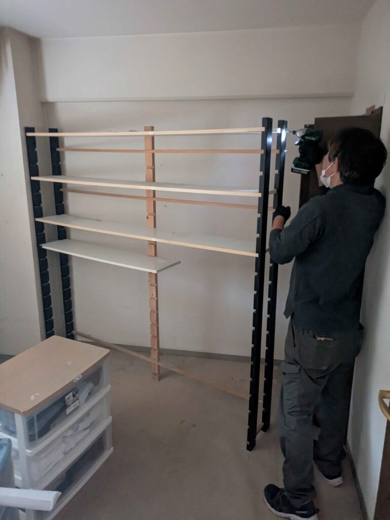 洋室のスチールラックを分解する当社スタッフ