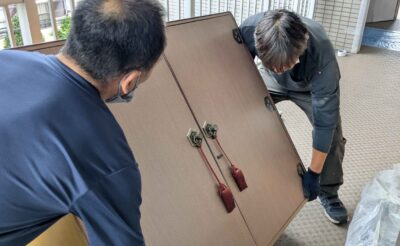 マンション4階の共用廊下で洋服ダンスを2人で運ぶ様子