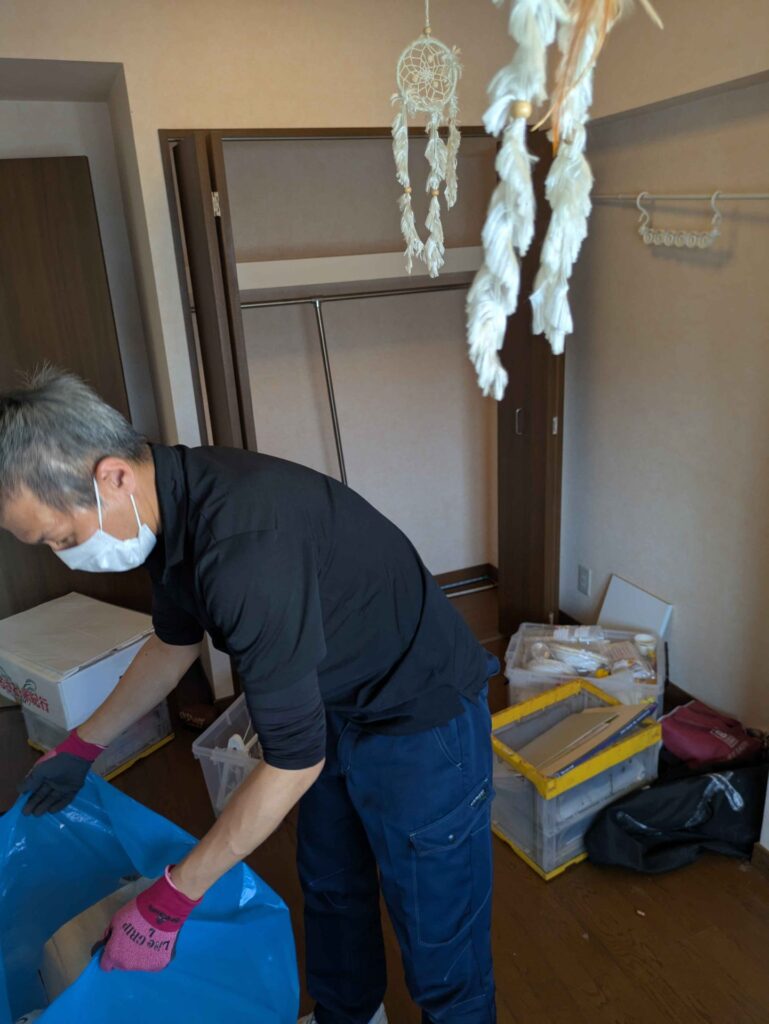 無人のお部屋で残された物を袋に詰めて分別する当社スタッフ