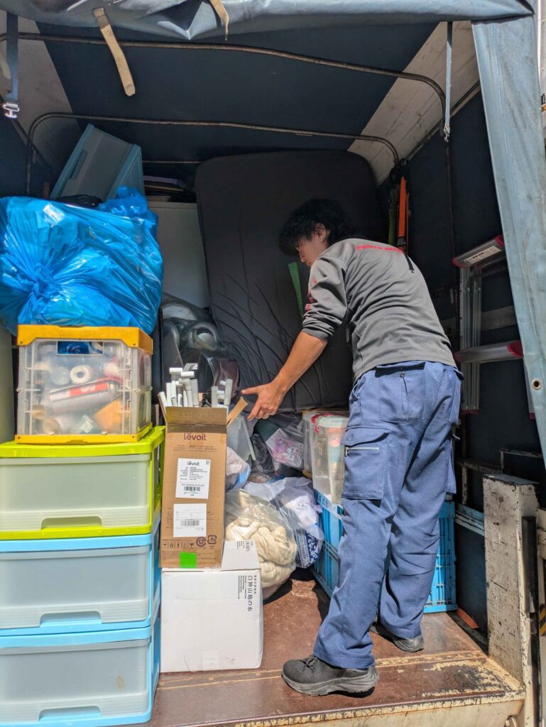 衣装ケースやコンテナ、ゴミ袋をトラックの荷台に積み上げる当社スタッフ