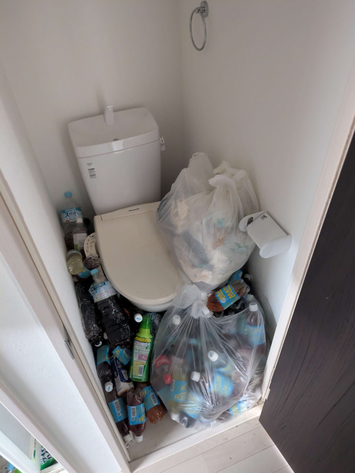 作業前：トイレの床にペットボトルとゴミ袋が置かれた様子