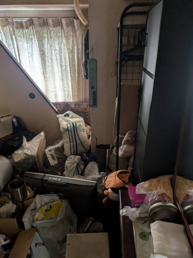 作業前:洋室に積まれた袋・家電・日用品