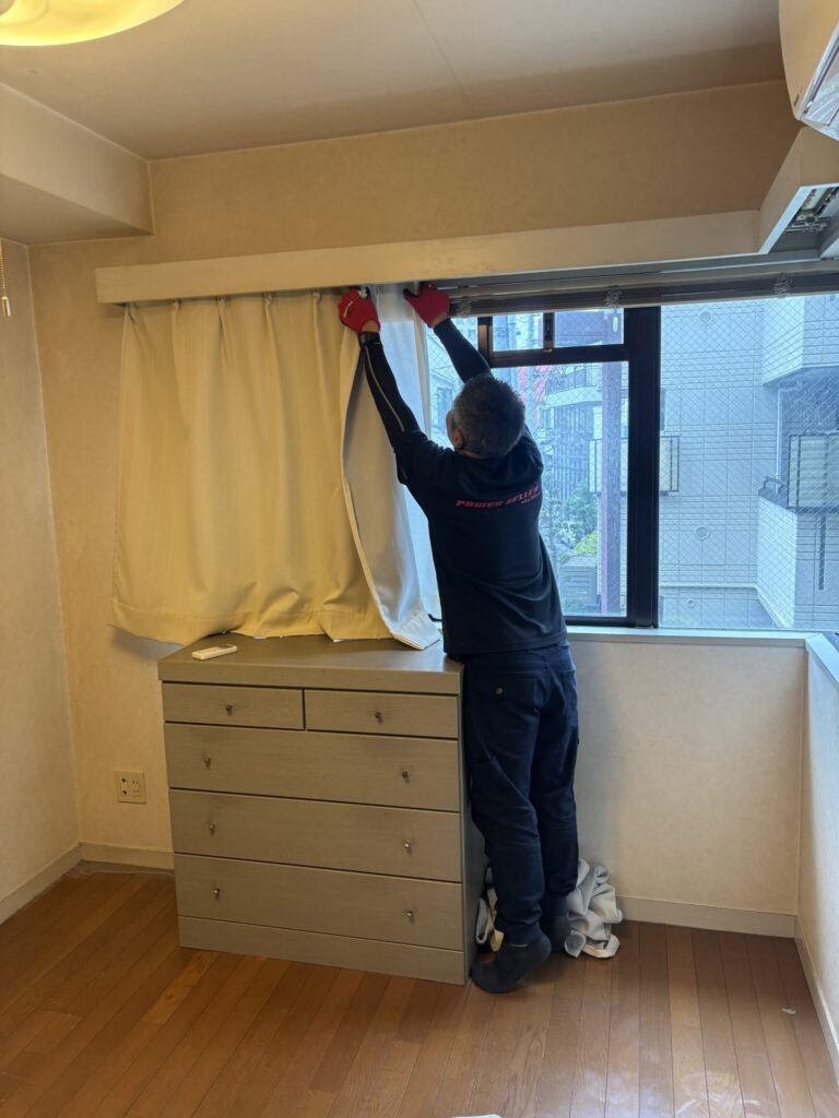 窓のカーテンを取り外す当社スタッフ