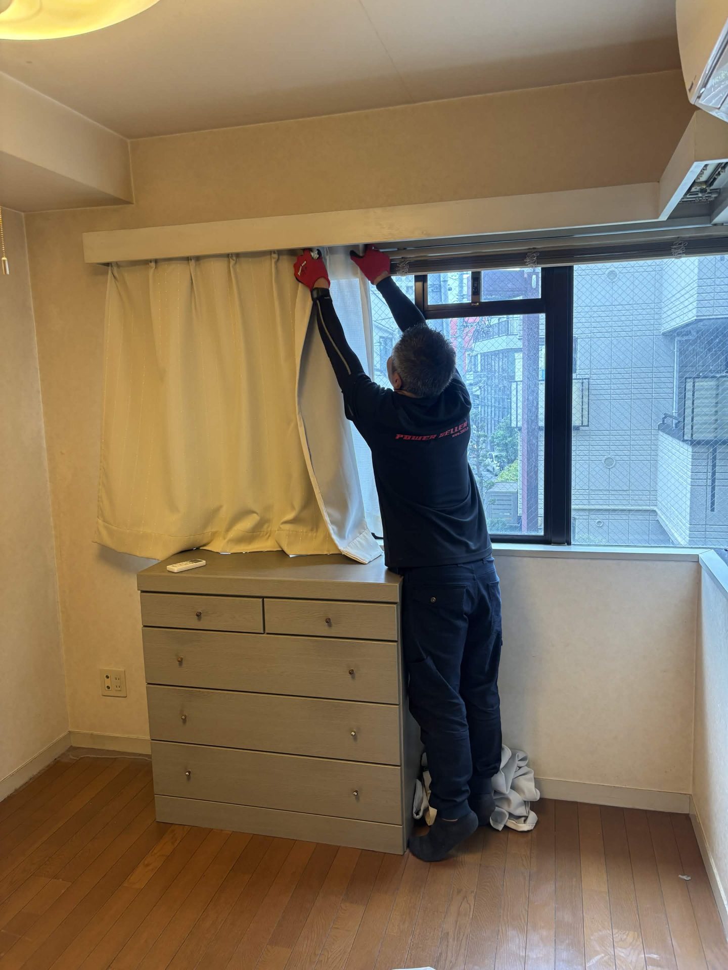 窓のカーテンを取り外す当社スタッフ