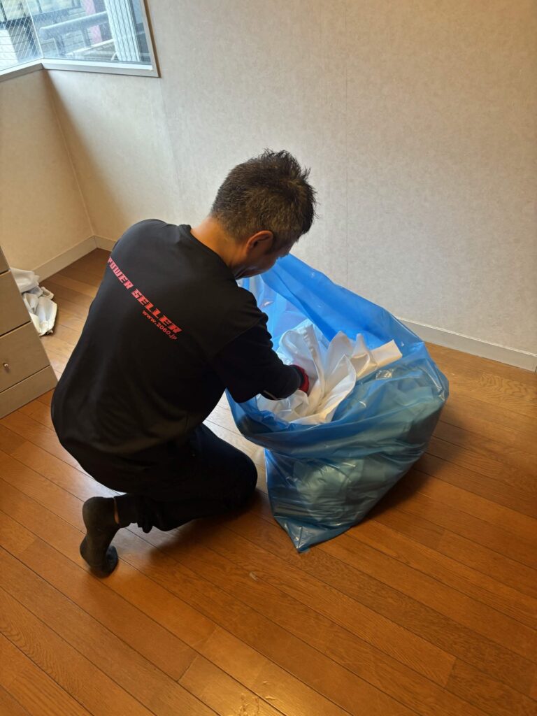 室内の小物を袋に詰めて分別する当社スタッフ