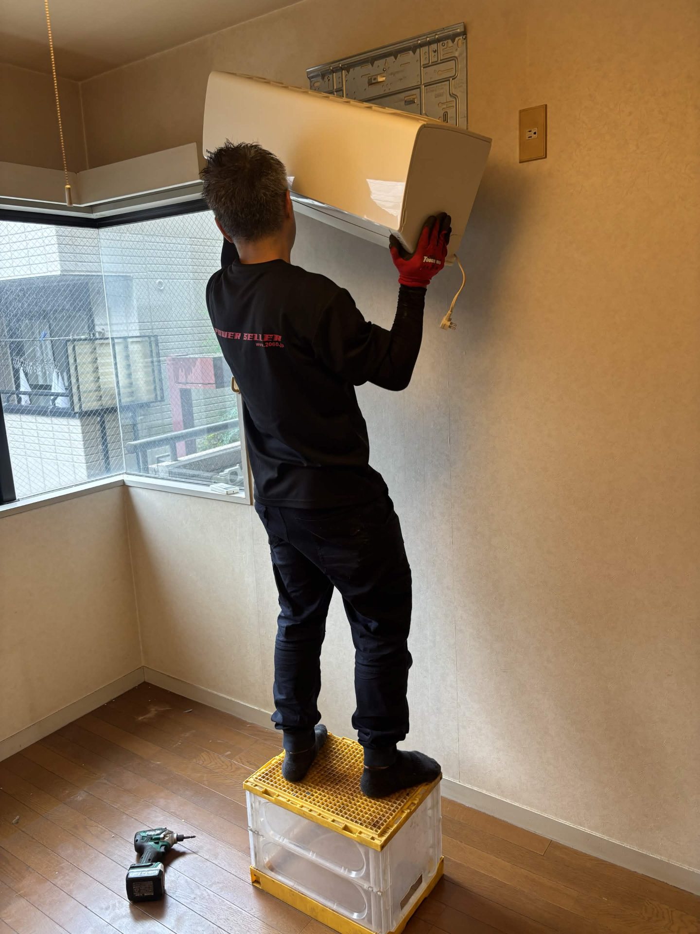 脚立に乗って照明器具を取り外す当社スタッフ