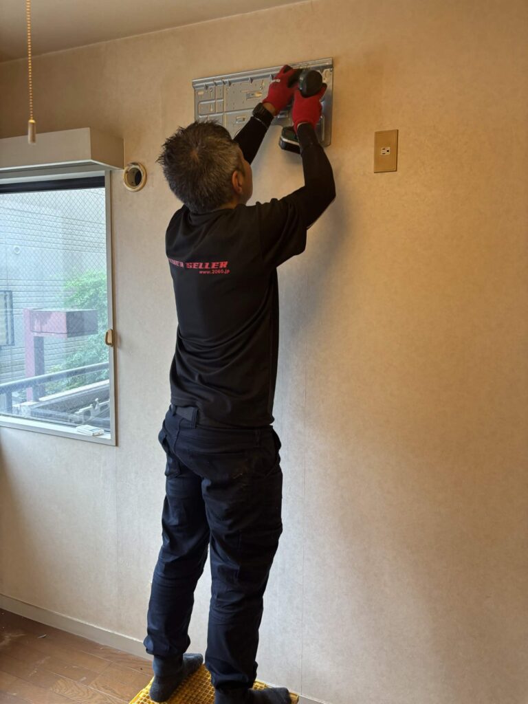 照明器具の取り付け金具を外す当社スタッフ
