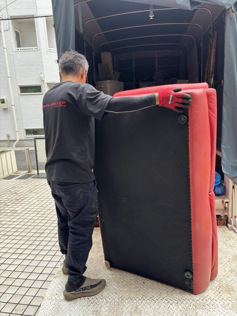 回収した赤いソファをトラックの荷台に積み込む当社スタッフ